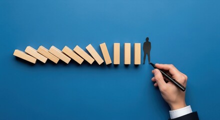 A hand in a suit stops a row of falling dominoes with a miniature person standing on the last one