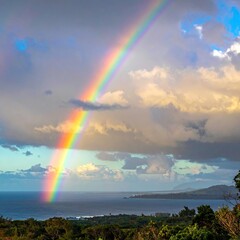 Vibrant rainbow arches over ocean, under a dramatic sky, and coastal landscape