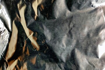 Crumpled silver metallic foil texture with shiny reflective light highlights