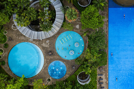 Aerial view of a symmetrical array of pools amidst verdant foliage at the Interlace Condominium, Telok Blangah, Singapore.