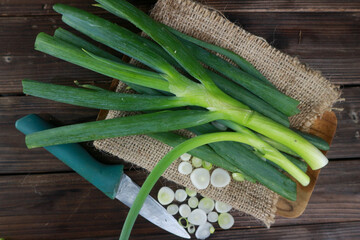 Fresh raw leeks on black wooden table, flat lay close up