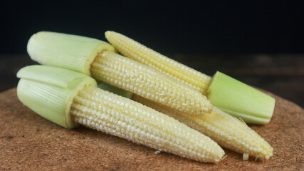 Close up fresh baby corn cobs with green husks