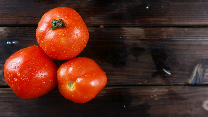 Fresh tomato resting on rustic wooden board serving as a background for text