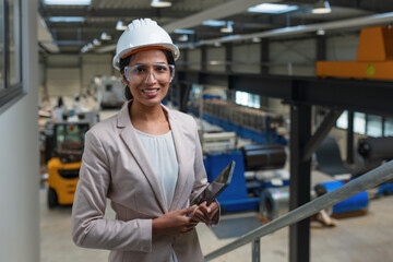 Young Indian woman, a successful metalworking factory manager writing notes after production...