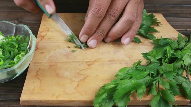 Woman hands chopping celery on cutting board. Housewife cooking fresh vegetables