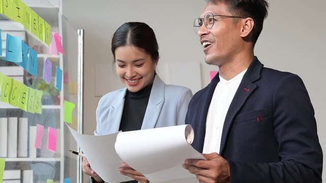 Business colleagues brainstorming ideas using sticky notes on a glass board