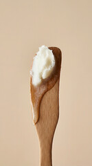 Close up of shea butter and honey on a wooden spatula against a neutral background