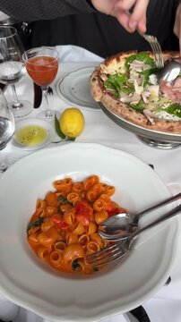 Hand holding fork over pasta dish in cozy Paris restaurant.