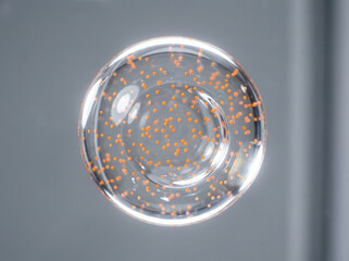 Close-up macro shot of orange caviar-like spheres suspended in clear liquid inside a glass bowl