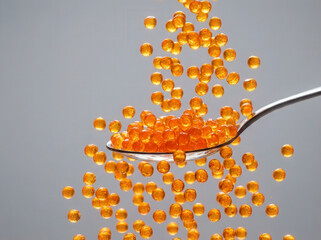Orange caviar falling from a spoon in a dynamic studio shot