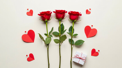 Romantic Flat Lay Composition of Three Vibrant Red Roses Surrounded by Paper Hearts and a Small Gift Box on a Cream Background