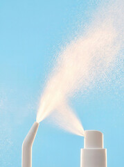 Two white spray bottles misting fine droplets against a bright blue background