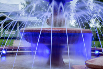 Fountain illuminated with multicolored light on a summer evening in the park