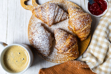 Fresh butter croissants on wooden board with coffee