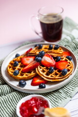 Waffles with strawberries and blueberries served with orange juice