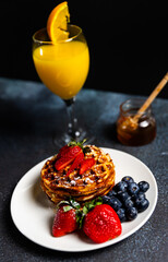 Waffles with strawberries and blueberries served with orange juice