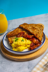 Scrambled eggs and bacon breakfast with toast and orange juice