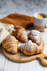 Fresh butter croissants on wooden board with coffee