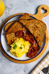 Scrambled eggs and bacon breakfast with toast and orange juice