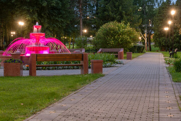 Fountain illuminated with multicolored light on a summer evening in the park