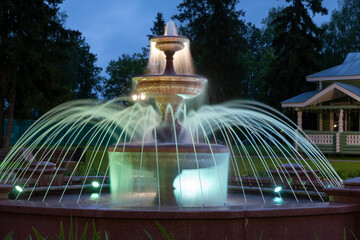 Fountain illuminated with multicolored light on a summer evening in the park