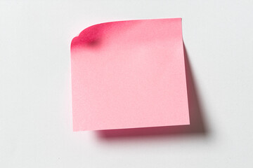 Blank pink sticky note on white wall. Template mock up