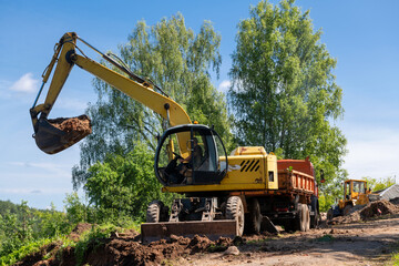 TETKOVO, Tver region, RUSSIA. An excavator loads earth into a truck