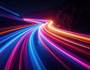 Long exposure shot of a curving road with colorful light trails against a dark mountain
