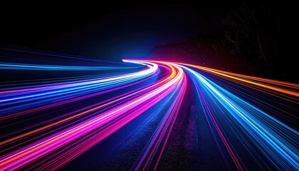 Long exposure captures vibrant light trails of vehicles streaking along a highway at night