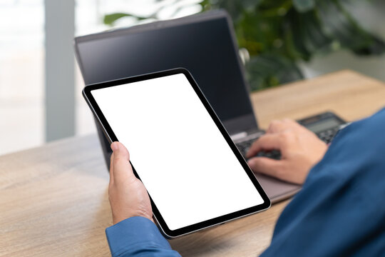 Businessman Holding Tablet with Blank White Screen for Text, Copy Space, Laptop and Calculator on Modern Office Desk, Financial Analysis, Business Plan, Online Transaction, Corporate Workspace Concept - Powered by Adobe