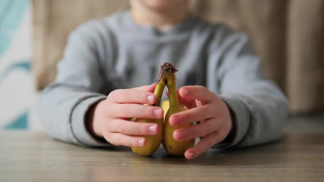 Child Snapping Apart Two Yellow Bananas for Healthy Snack Time