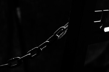 Chain link for closure in low key lighting with room for text on black background.