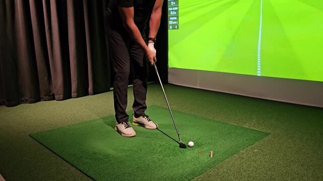 Golf practice indoors with swing training and ball tracking at a sports facility in the evening