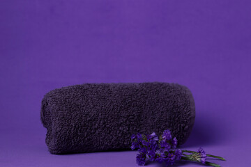 Soft towel and purple flowers on a purple background for relaxation or spa setting