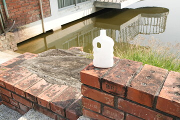 White Plastic Bottle on a Brick Wall by a Body of Water