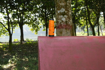 Orange Thread Spool on Red Ledge by the Water