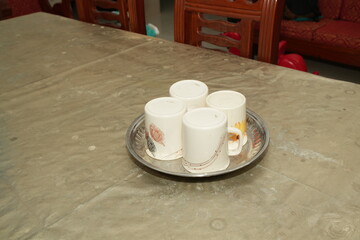 Four White Mugs with Lids on a Silver Tray on a Table