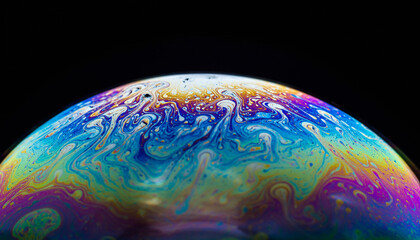 Macro close-up of a soap bubble's surface displaying swirling, vibrant iridescent colors and abstract patterns due to thin-film interference against a dark background.