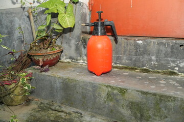 Orange Pump Sprayer on Concrete Step with Potted Plants