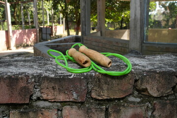 Green Jump Rope with Wooden Handles on a Brick Wall
