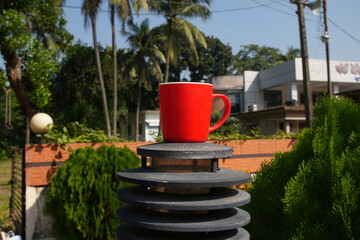 Bright Red Mug Resting on a Garden Light on a Sunny Day