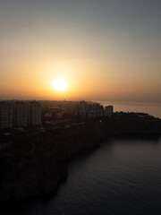 Drone flight over sea surface reflecting the orange sun at dusk