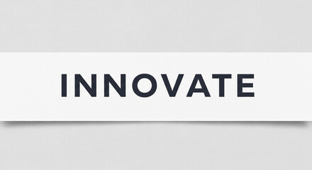 The image displays the word "INNOVATE" in bold, dark blue letters on a white rectangle, over a gray textured surface, representing creative progress