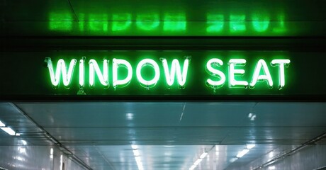 Bright green neon sign displays WINDOW SEAT twice. Tunnel interior provides dark backdrop. Minimalist aesthetic, modern design.
