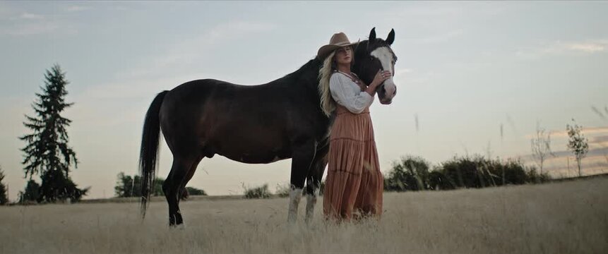 Cowgirl model with horse in open field at sunset, western lifestyle