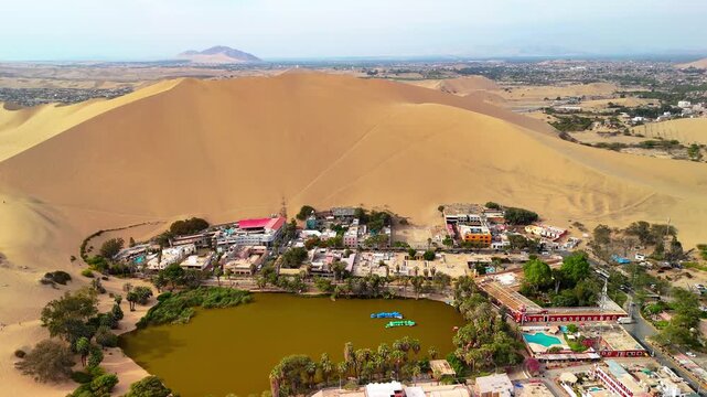 Aerial drone view of a desert landscape with the Huacachina oasis, sand dunes and the city of Ica. Peru