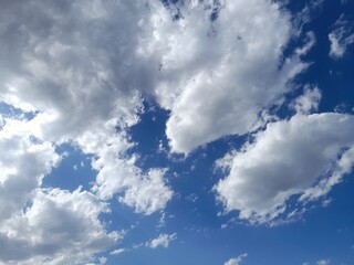 White fluffy clouds on a clear blue sky background 