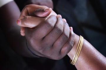 Close-up view of two people holding hands, symbolizing love, care, trust, emotional support, and human connection.