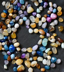 Collection of colorful polished gemstones arranged on a dark background, representing minerals, healing crystals, jewelry materials, and natural textures.