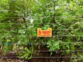 High voltage danger warning sign with skull symbol displayed on electric line in India, highlighting electrical hazard, safety awareness and public warning signage.